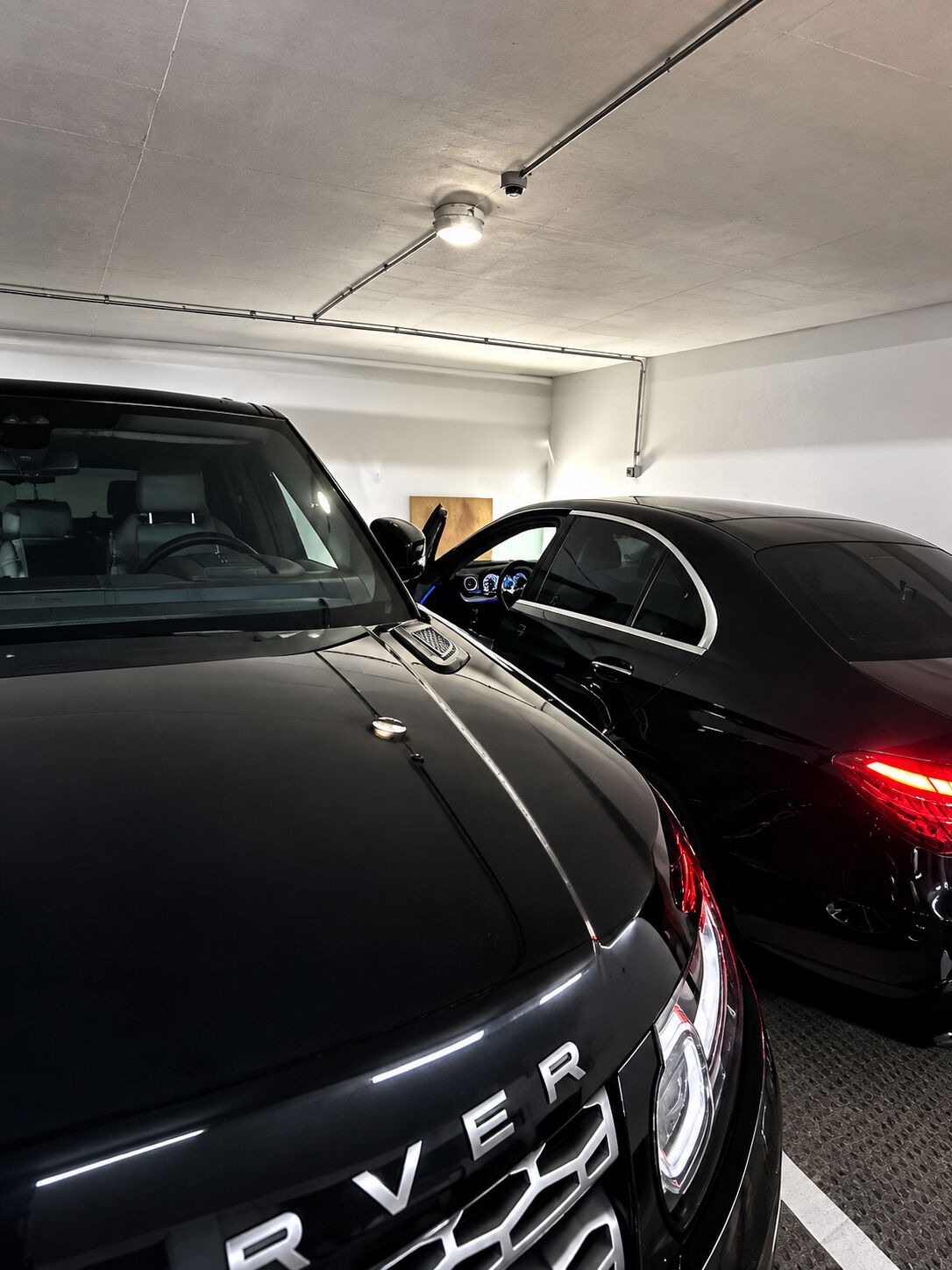 Range Rover e Mercedes pretos lado a lado numa garagem