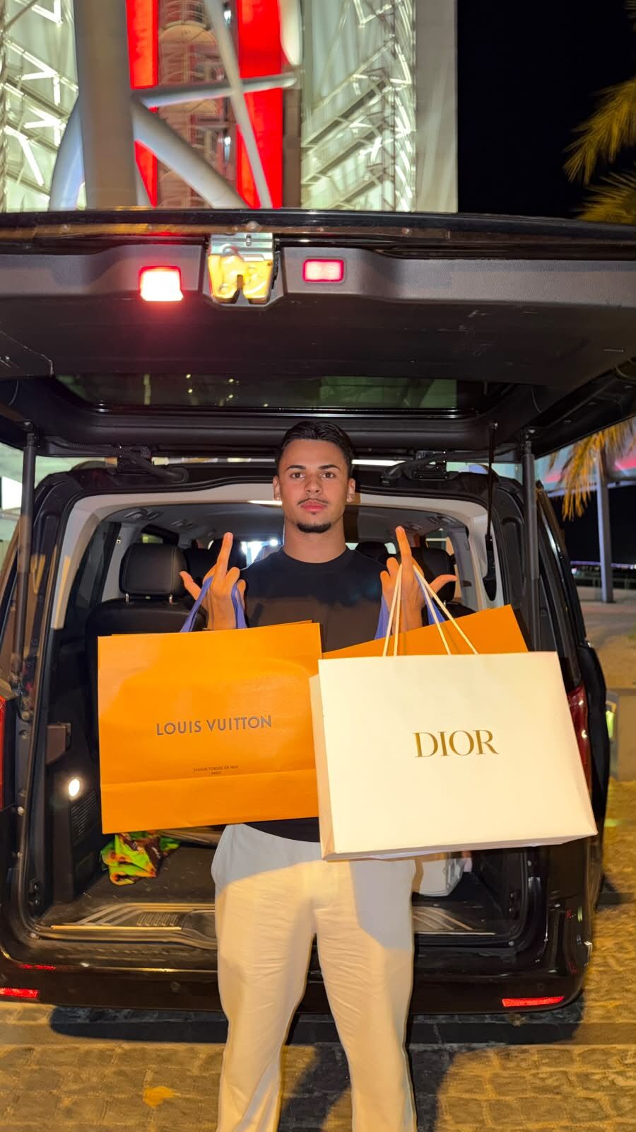 usantana à frente de uma carrinha com sacos de compras Louis Vuitton e Dior